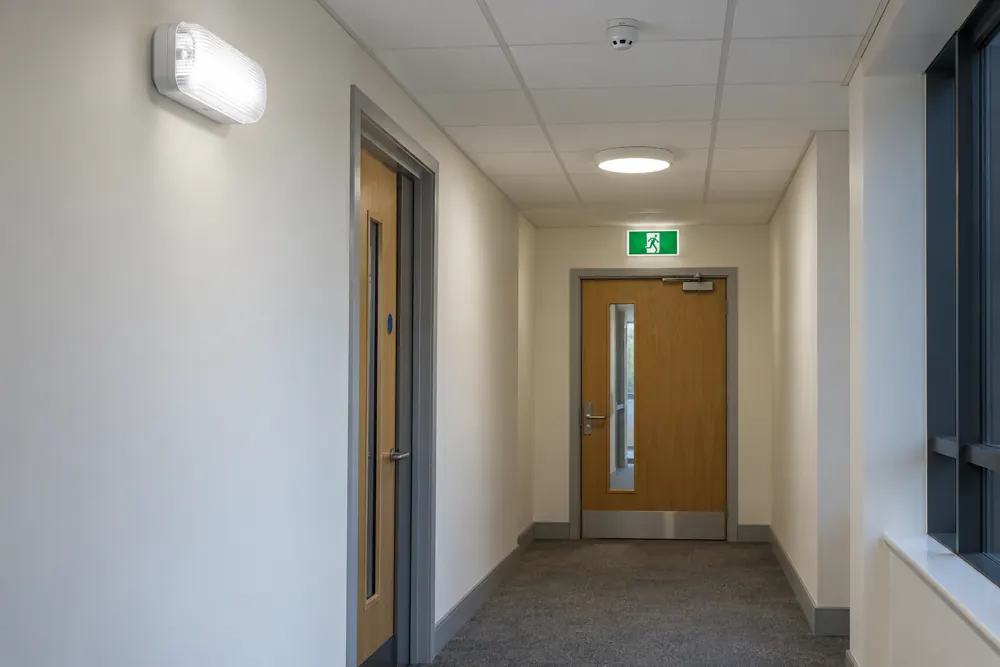 Emergency light fittings along an empty commercial escape corridor
